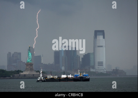 Dunkle Wolken und ein Blitz Blitz hinter der Statue of Liberty, Jersey City am Rücken, New Jersey, New York, USA Stockfoto