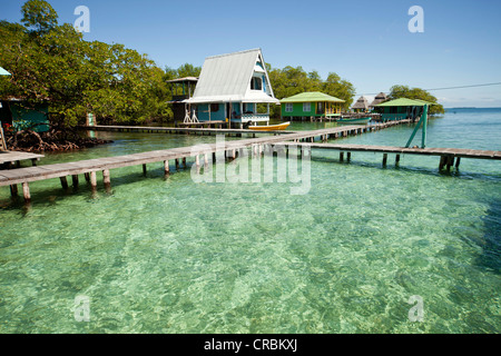 Steg in das klare Wasser und ein typisches Holzhaus auf der kleinen karibischen Insel Coral Key, Bocas del Toro, Panama Stockfoto