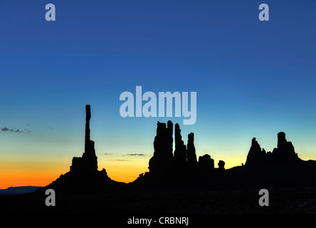 Totempfahl und Yei Bi Chei Felsformationen mit Hintergrundbeleuchtung vor Sonnenaufgang, Morgendämmerung, Monument Valley Navajo Tribal Park Stockfoto