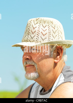 Älterer Mann mit Strohhut im freien Stockfoto
