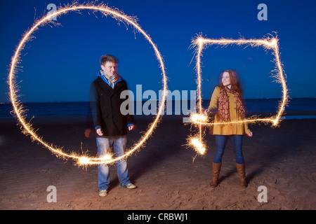Paar mit Wunderkerzen am Strand spielen Stockfoto