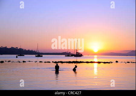 Menschen Baden bei Sonnenaufgang, Boote in der Bucht von Puerto de Pollensa, Port de Pollenca, Mallorca, Balearen Stockfoto