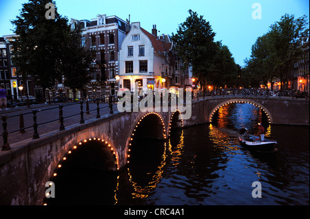 Beleuchtete Brücke und Wohnhäuser in der Dämmerung, Prinsengracht, Leliegracht, Stadtgracht im historischen Zentrum der Stadt, Stockfoto