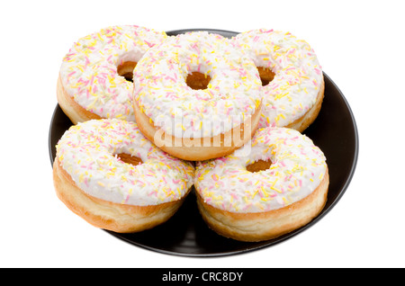 Ring-Donuts auf einer schwarzen Platte angeordnet. Studio mit einem weißen Hintergrund gedreht. Stockfoto