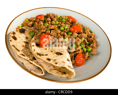 Ein Teller mit Rindfleisch oder Lamm Curry mit Erbsen und Kirschtomaten und Chapatis, isoliert auf weiss, und Clipping-Pfad enthalten. Stockfoto