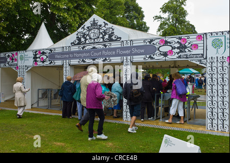 Besucher nach RHS Hampton Court Flower Show 2011 in Macs und mit Sonnenschirmen Stockfoto