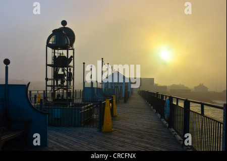 Wasser-angetriebene Uhr auf Southwold Pier in einem dicken Meer Bund wie die Sonne bricht durch Stockfoto