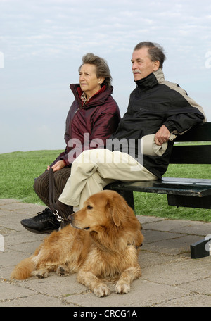 Hovawart (Canis Lupus F. Familiaris), älteres Paar mit Hund auf Bank sitzend Stockfoto
