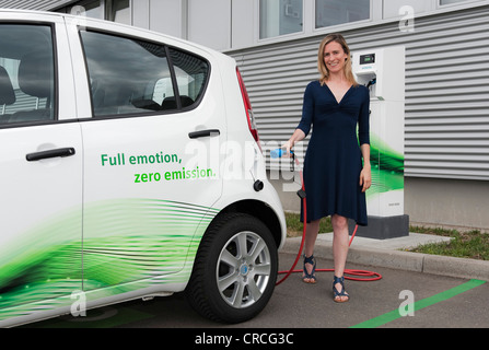 Frau hält eine Ladestation stecken für eine Suzuki Splash-Elektro-Auto, vor einer Ladesäule Charge CP700A von Siemens, Fürth Stockfoto