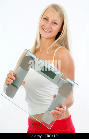 schlanke, junge Frau, die eine Skala in ihren Händen hält Stockfoto