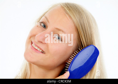 junge Frau Bürsten ihre langen blonden Haare Stockfoto