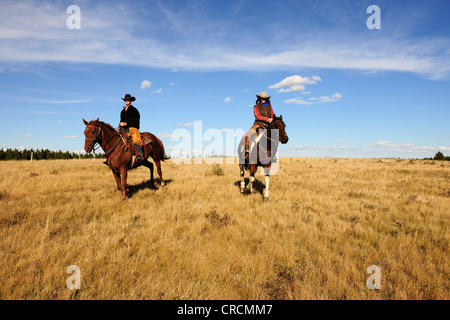 Ein Cowgirl und ein Cowboy Reiten quer durch die Prärie, Saskatchewan, Kanada Stockfoto