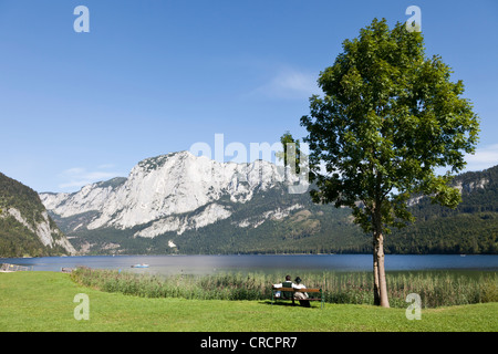 Junges Paar tragen traditionelle Kostüm sitzt auf einer Parkbank in Altaussee-See, Salkkammergut, Österreich Stockfoto