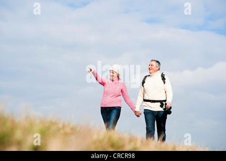 Paare, die Hand in Hand in Wiese Stockfoto