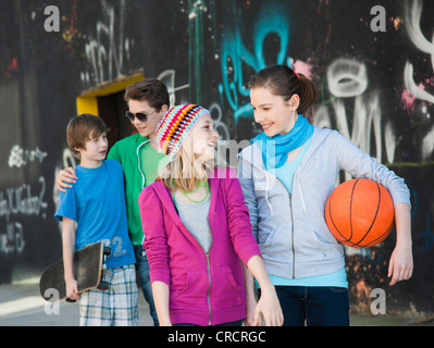 Vier glückliche Teenager Freunde zu Fuß in der Graffitiwand Stockfoto