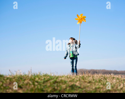 Mädchen stehen auf Wiese mit Spielzeug Windmühle Stockfoto