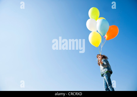 Mädchen mit Luftballons unter blauem Himmel steht Stockfoto