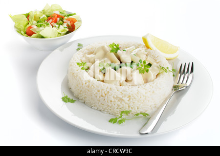 Hühnerfrikassee mit Spargel, Erbsen und Pilze in einem Ring von Reis, Schüssel mit Salat Stockfoto