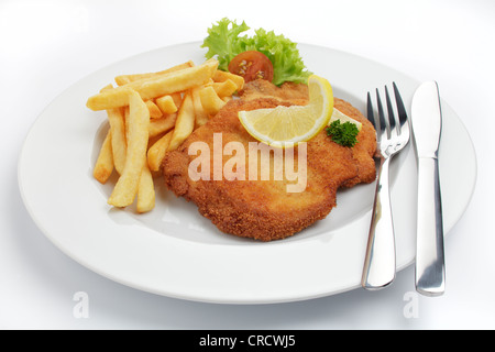 Paniertes Schweinefleisch Schnitzel Wiener Art mit Zitronenscheibe und Pommes frites Stockfoto