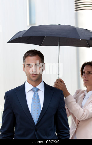 Geschäftsfrau Holding-Dach oberhalb Geschäftsmann Stockfoto