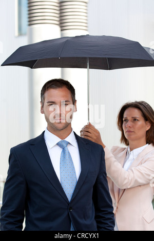 Geschäftsfrau Holding-Dach oberhalb Geschäftsmann Stockfoto