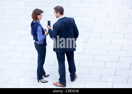 Unternehmer und Unternehmerin mit Handy im Freien stehen Stockfoto