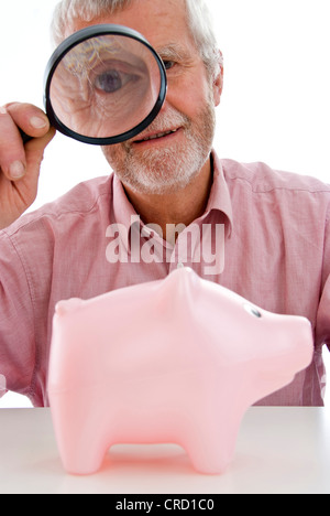 Rentner, die gerade Piggy Bank unter der Lupe Stockfoto