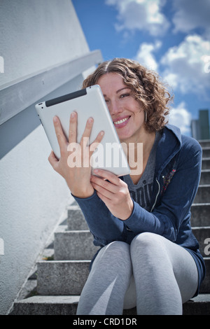 Frau sitzt mit dem Ipad auf Treppe Stockfoto