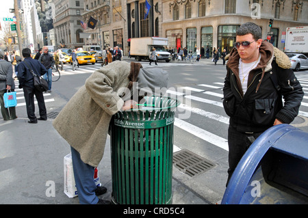 ein Obdachloser auf der Suche nach verwertbare Dinge in einem Mülleimer, USA, New York City, Manhattan Stockfoto