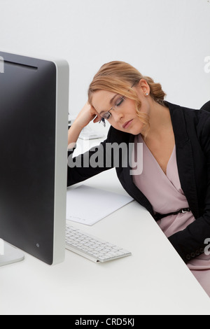 Junge Frau mit geschlossenen Augen am Schreibtisch Stockfoto