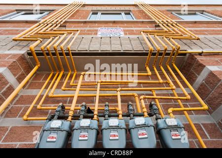 Fünf Enbridge Gaszähler und Rohre bis zum Dach.  Eine Reihe von Gaszählern, die durch ein komplexes Labyrinth von gelben Rohren verbunden Stockfoto