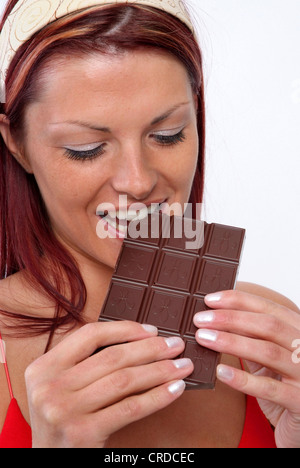 junge Frau, die einen Schokoriegel essen Stockfoto