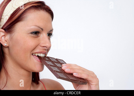 junge Frau, die einen Schokoriegel essen Stockfoto
