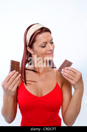 junge Frau betrachten die beiden Hälften einer Tafel Schokolade Stockfoto