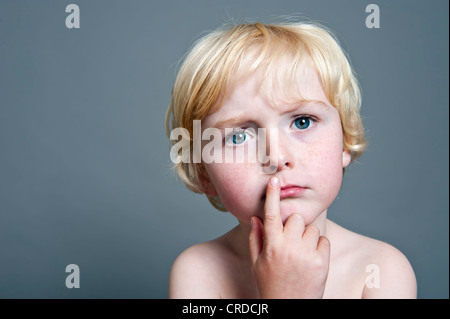 Five-Year-Old Boy nachdenklich setzen seine Finger an den Mund, Porträt Stockfoto