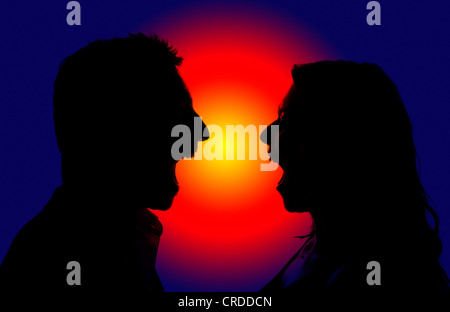 Ein Mann und eine Frau schreien sich gegenseitig, Silhouette gegen ein rotes und blaues Licht Stockfoto