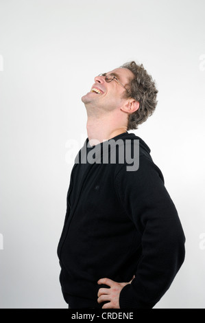 Junger Mann mit Brille Lachen herzhaft, Hände auf den Hüften Stockfoto