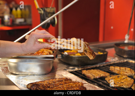 Hand, die Grillzange mit einem Braten Wurst, Bratwurst, Deutschland, Europa Stockfoto