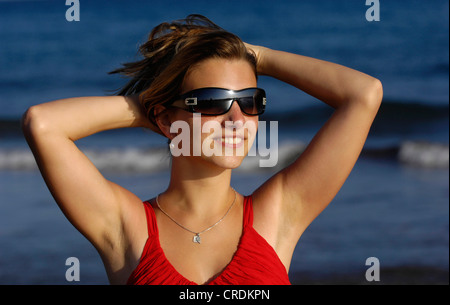 junge nette Frau am Strand, mit den Armen hinter dem Kopf Stockfoto