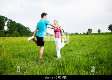 Junges Paar tun stretching-Übungen auf einer Wiese Stockfoto