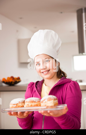 Mädchen in eine Kochmütze präsentieren einen Berliner oder Krapfen gefüllt Stockfoto