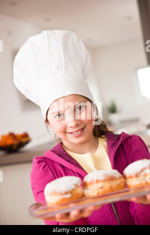 Mädchen in eine Kochmütze präsentieren einen Berliner oder Krapfen gefüllt Stockfoto