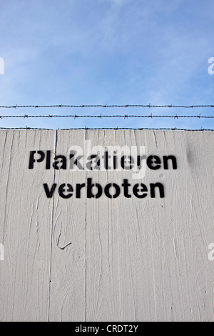 Besprüht-Schriftzug "Plakatieren verboten" oder "keine Plakate" auf einem Zaun mit Stacheldraht Stockfoto