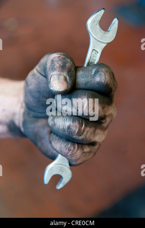 Alten bedeckten Hand hält einen Gabelschlüssel, Kfz-Mechaniker, Mechatroniker, arbeiten in der Instandhaltung Stockfoto