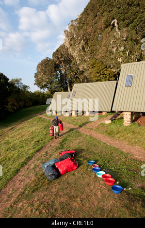 Bergsteigen, trekking, Gepäckträger mit Gepäck vor Berg Hütten, Kunststoff-Schalen für das Waschen, Mandara Hütte, Marangu-route Stockfoto