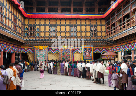 Tibetisch-buddhistische Festival Gewand Menschen tragen die traditionelle Gho stehen in einer Warteschlange, Rinpung Dzong Kloster und Festung Stockfoto