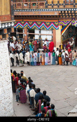 Tibetisch-buddhistische Festival Gewand Menschen tragen die traditionelle Gho stehen in einer Warteschlange, Rinpung Dzong Kloster und Festung Stockfoto