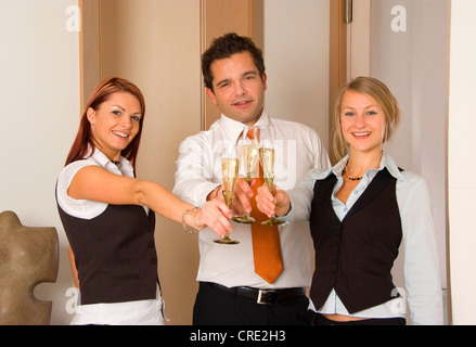 drei junge Geschäftsleute klirrende Gläser mit Sekt Stockfoto