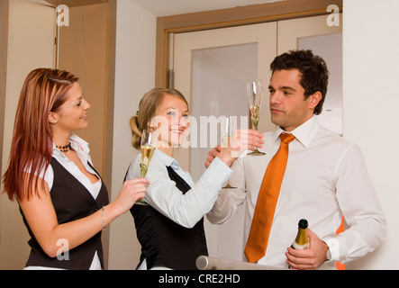 drei junge Geschäftsleute klirrende Gläser mit Sekt Stockfoto