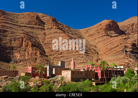 Kleines Dorf mit einer Moschee vor roten Felswänden, Ait Mansour Tal, Anti-Atlas-Gebirge, Südmarokko, Marokko Stockfoto